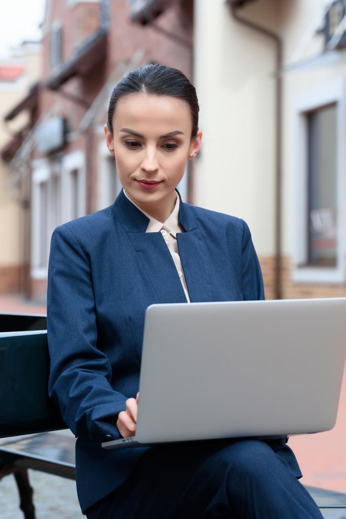 красива бізнес-леді використовує ноутбук на лавці
 - Фото, зображення
