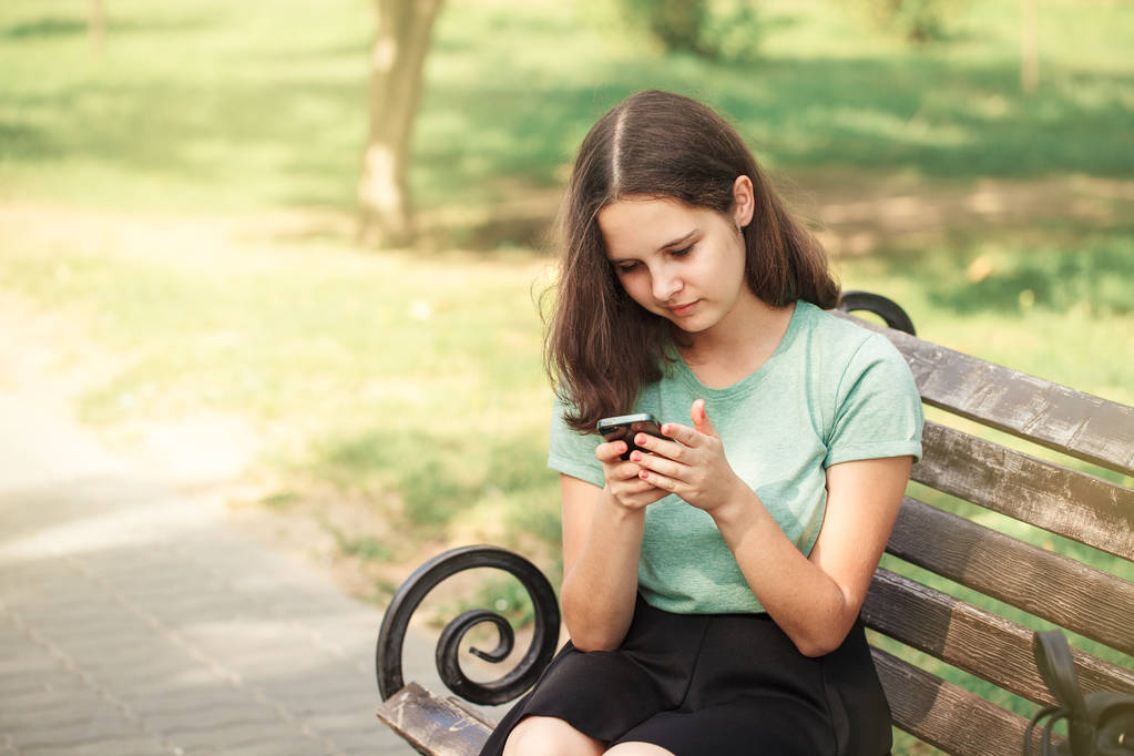 όμορφη κοπέλα έφηβος με smartphone σε καλοκαιρινά χέρια στο πάρκο - Φωτογραφία, εικόνα
