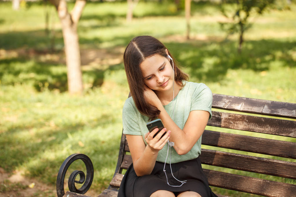 Hermosa adolescente en audífonos escuchando música en el parque.. - Foto, Imagen