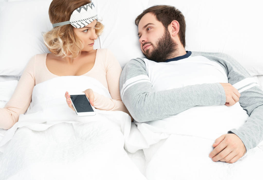 Ζευγάρι κοιμούνται μαζί στο κρεβάτι. Γυναίκα με τη χρήση της έξυπνο τηλέφωνο - Φωτογραφία, εικόνα