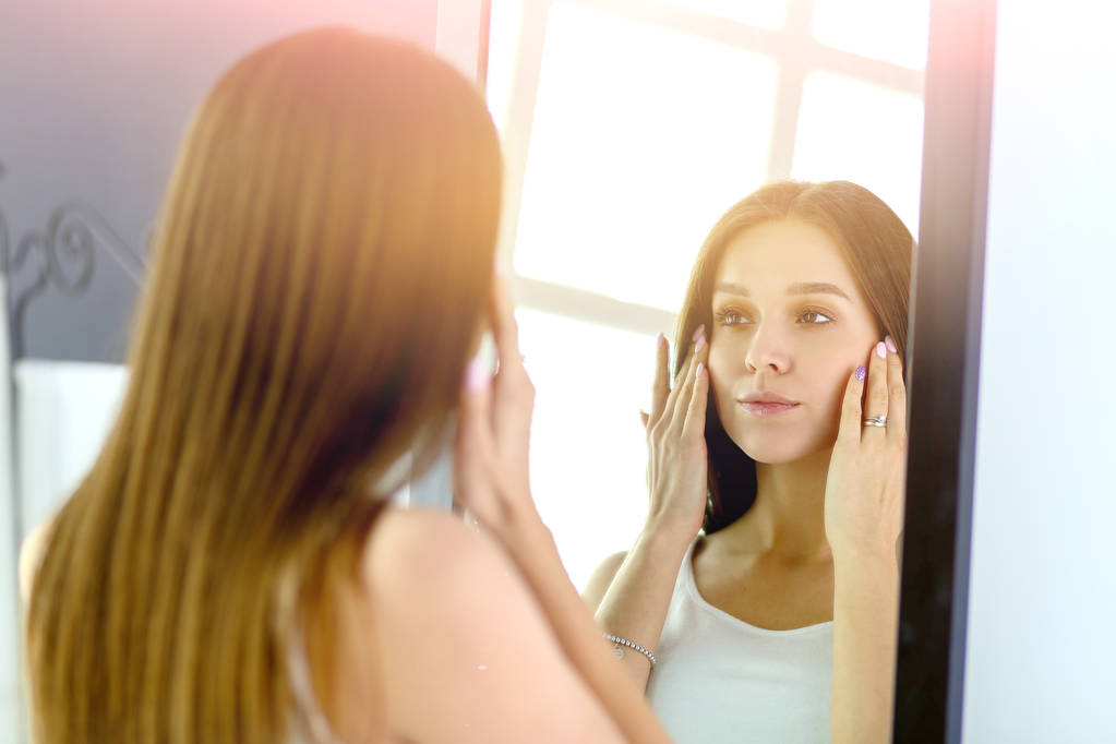 Jeune femme se regardant réflexion dans le miroir à la maison
 - Photo, image