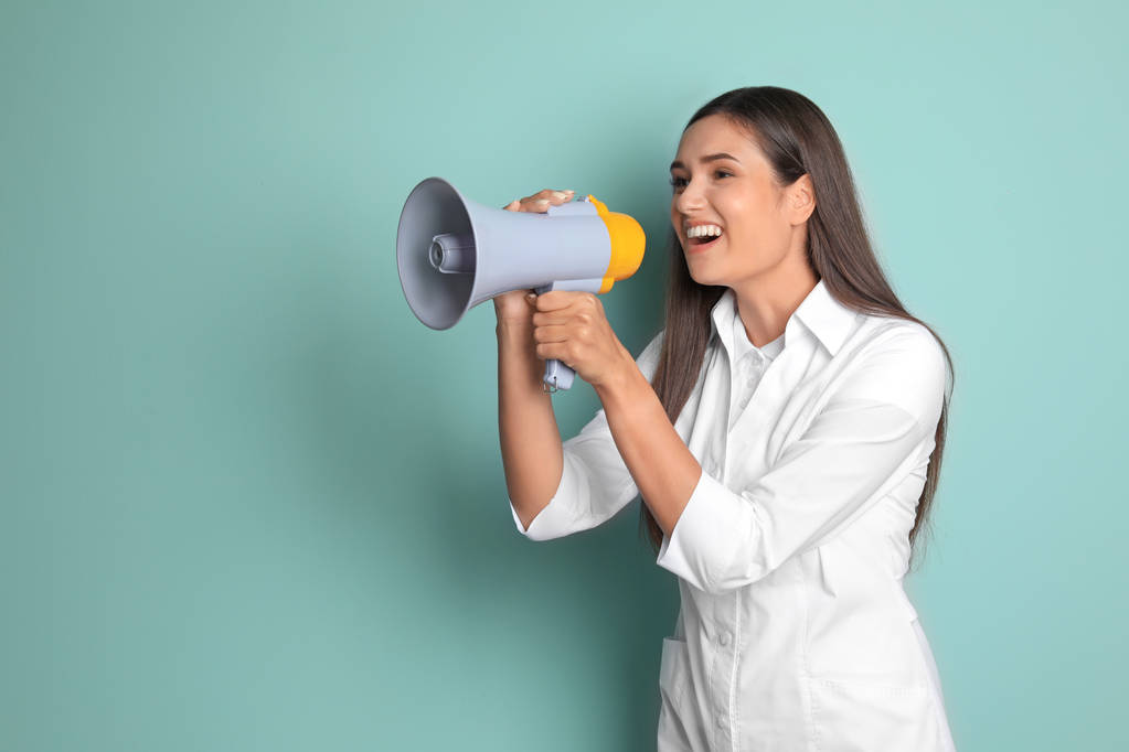 Giovane medico femminile utilizzando megafono su sfondo di colore
 - Foto, immagini