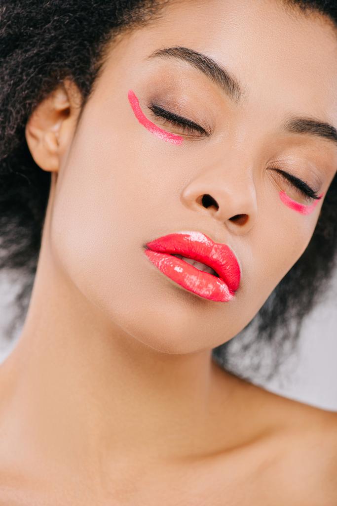 sinnliche junge Frau mit roten Lippen und roten Farbstrichen unter geschlossenen Augen isoliert von grau - Foto, Bild