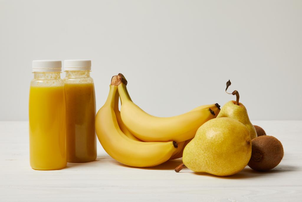 muz, armut ve kivi beyaz zemin üzerine sarı smoothies ile şişe   - Fotoğraf, Görsel