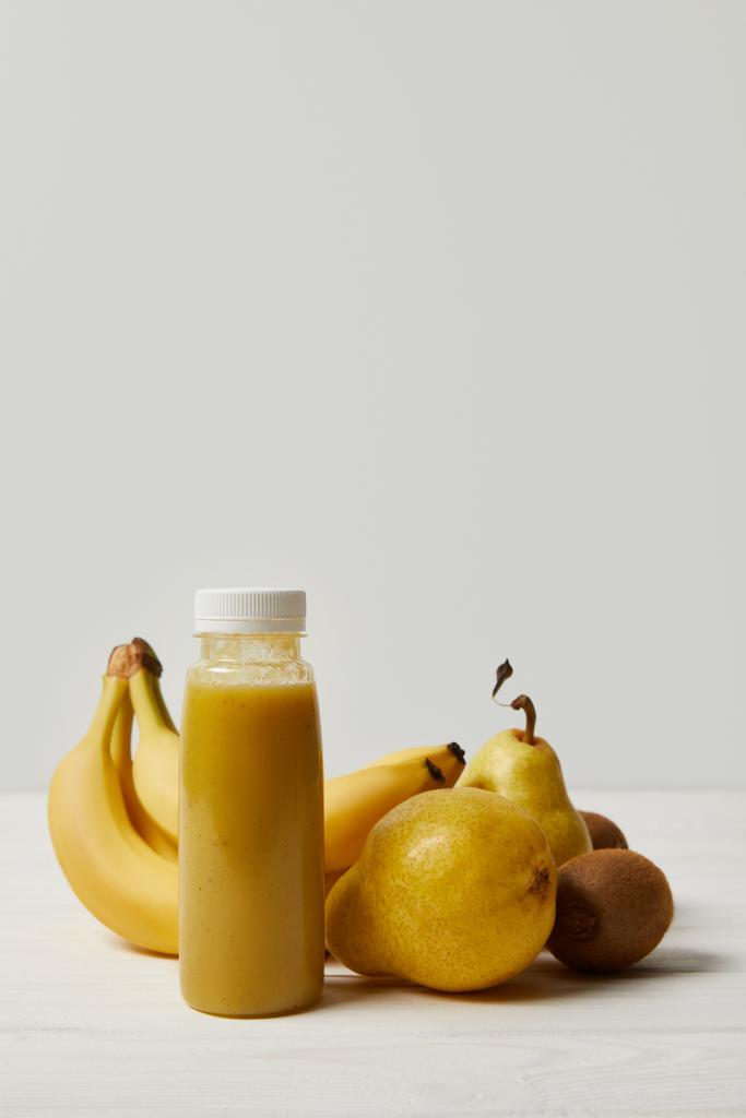 バナナ、キウイ、白い背景の上の梨をボトルに黄色デトックス スムージー   - 写真・画像