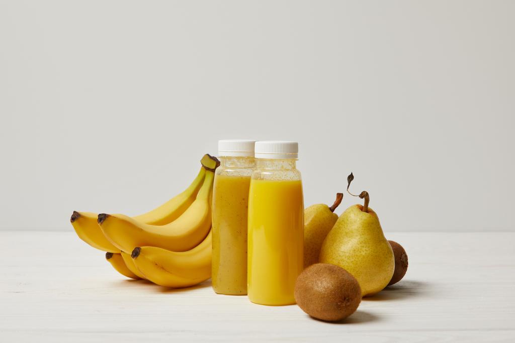 バナナと梨とキウイの白い背景の上のボトルに黄色のデトックス スムージー   - 写真・画像