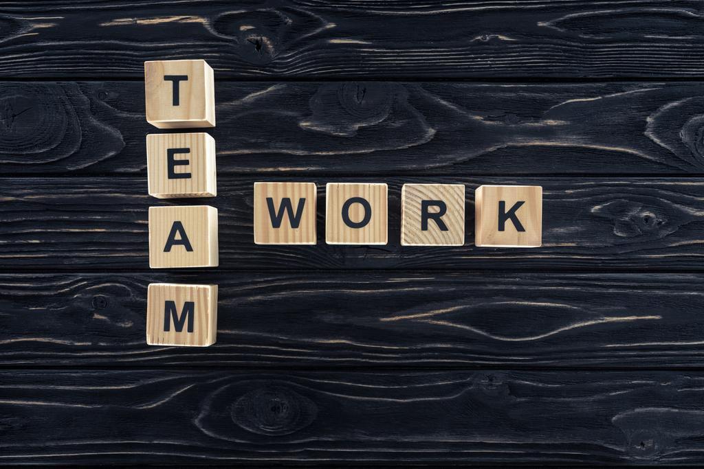 top view of team work words made of wooden blocks on dark wooden tabletop - Photo, Image