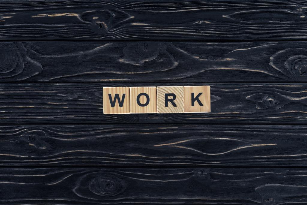 pohled shora slovo práce z dřevěných bloků na tmavé dřevěné stolní - Fotografie, Obrázek