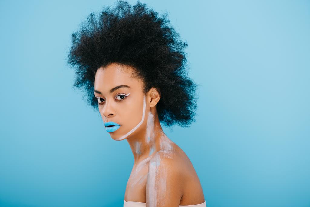 mooie jonge vrouw met creatieve make-up en afro kapsel geïsoleerd op blauw - Foto, afbeelding