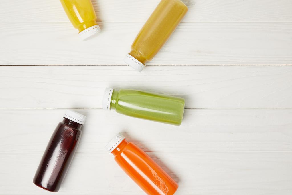вид свежих красочных коктейлей в бутылках на белом деревянном фоне
  - Фото, изображение