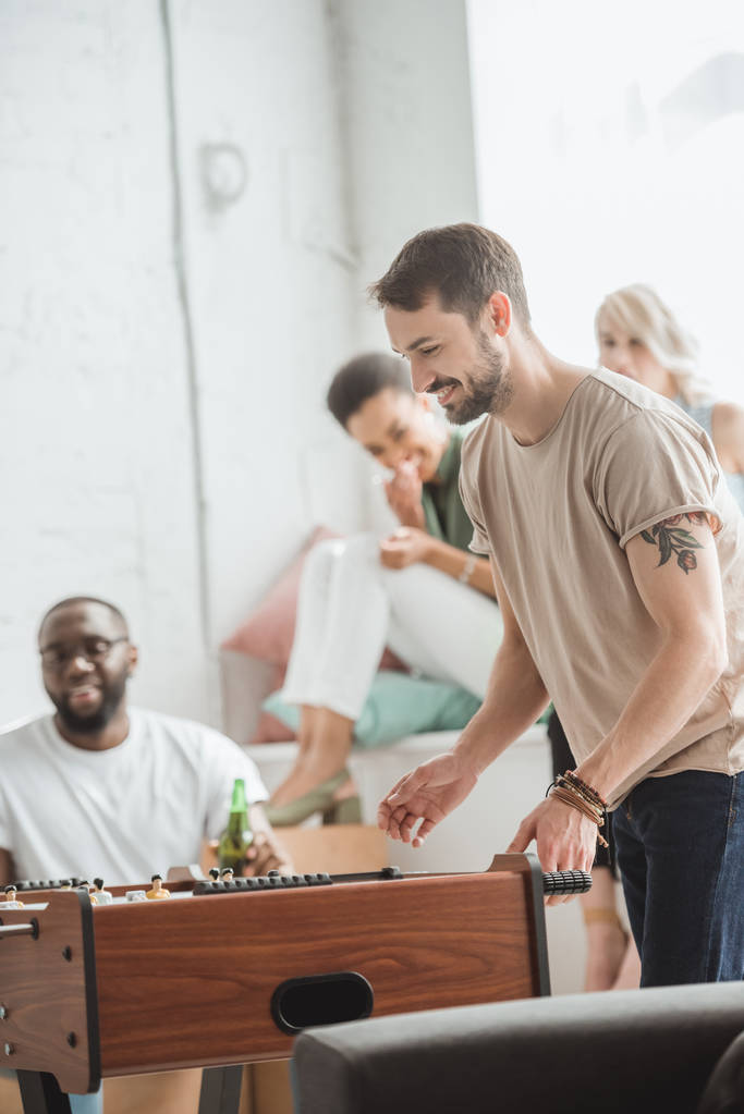 smiling man playing table football while friends watching  - Photo, Image