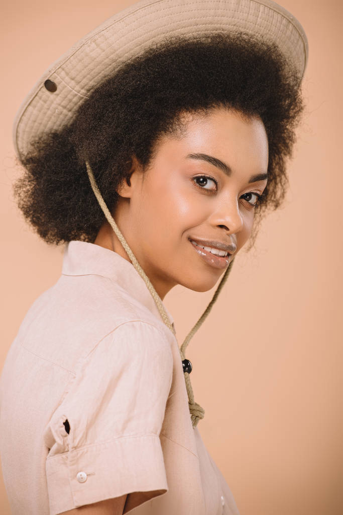 Close-up πορτρέτο της ευτυχισμένη αφρικανική αμερικανική γυναίκα με καπέλο σαφάρι που απομονώνονται σε μπεζ - Φωτογραφία, εικόνα