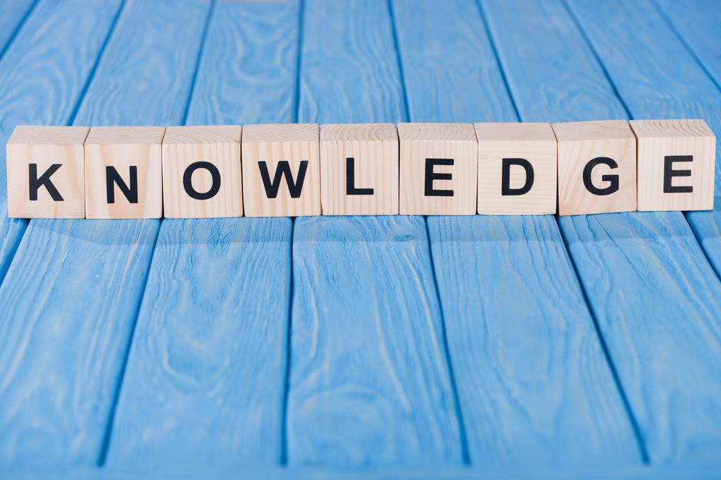 close up view of knowledge word made of wooden blocks on blue tabletop - Photo, Image