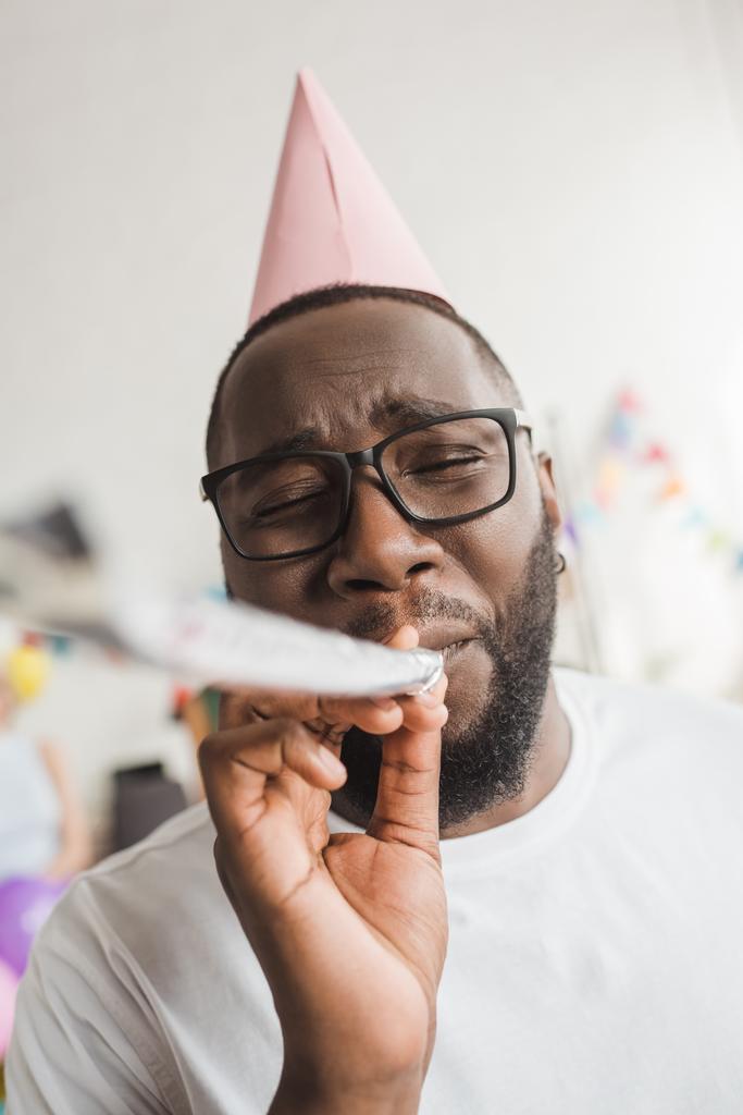 Happy african american in party hat blowing party horn - Photo, Image
