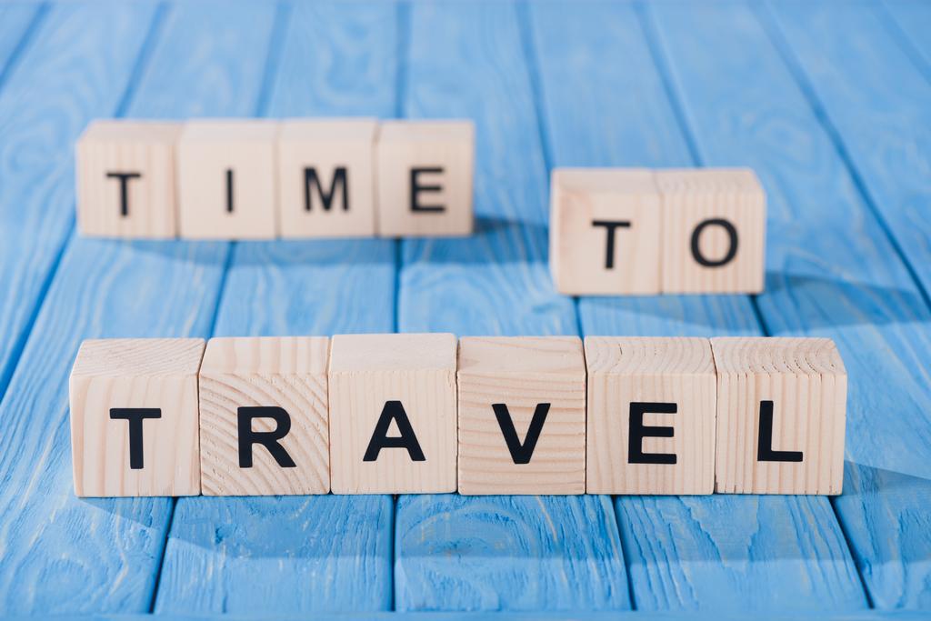 close up view of arranged wooden blocks into time to travel phrase on blue wooden surface  - Photo, Image