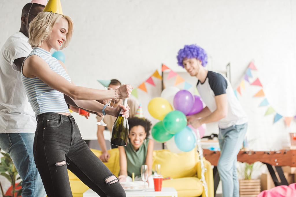 Blond žena otevírání šampaňského před párty přátel - Fotografie, Obrázek
