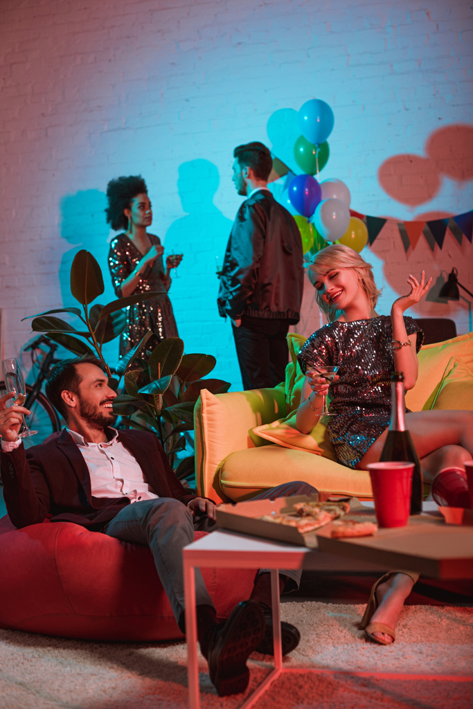 Улыбающиеся молодые люди наслаждаются выпивкой и разговаривают на вечеринке
 - Фото, изображение