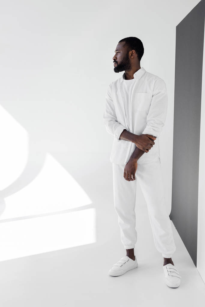 knappe Afro-Amerikaanse man in witte trendy kleren weg op zoek  - Foto, afbeelding