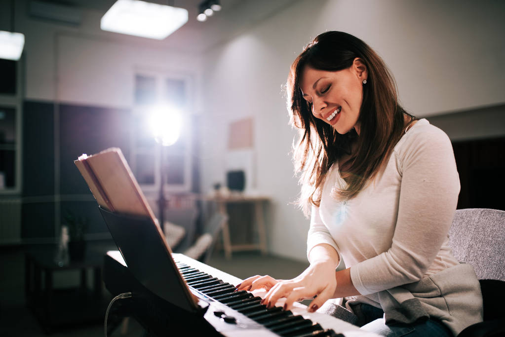 Гарненька жінка насолоджується грою на піаніно
. - Фото, зображення