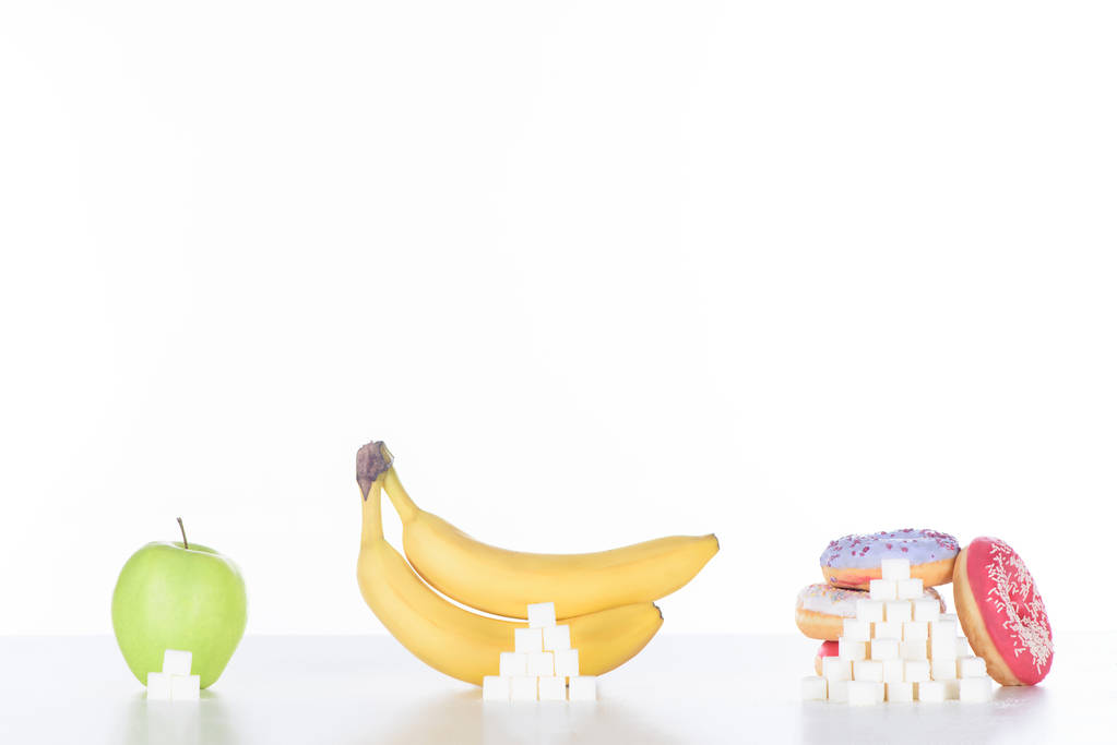 mela, banane e ciambelle con cubetti di zucchero su bianco
 - Foto, immagini