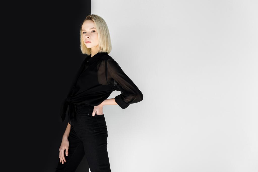 atrakcyjne stylowej kobiety Blondynka w czarne ubrania pozowanie w pobliżu czarno-białe ściany - Zdjęcie, obraz