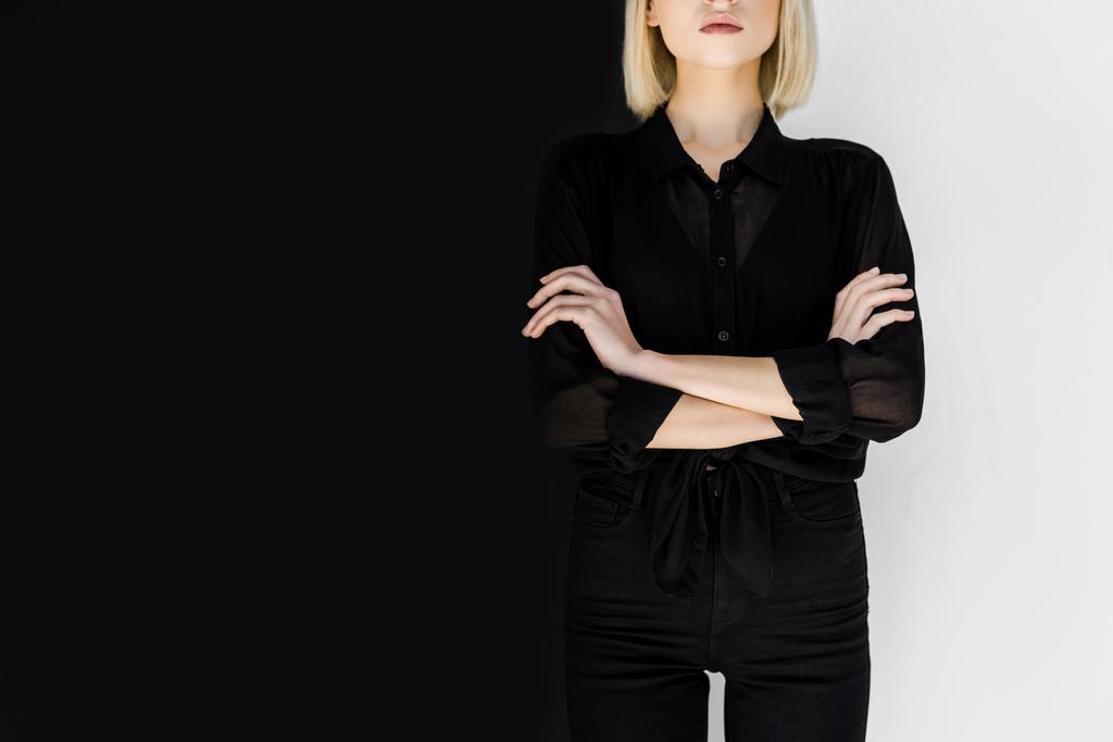 image recadrée de femme blonde élégante en vêtements noirs debout avec les bras croisés
 - Photo, image