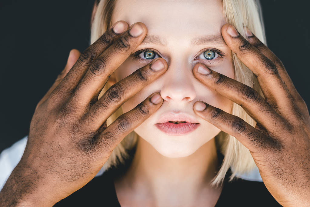 abgeschnittenes Bild eines afrikanisch-amerikanischen Freundes, der blonde Freundin berührt, Gesicht isoliert auf schwarz - Foto, Bild