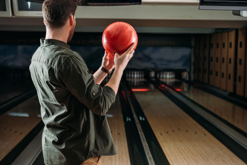 rear view of man with bowling ball looking at alleys - Photo, Image