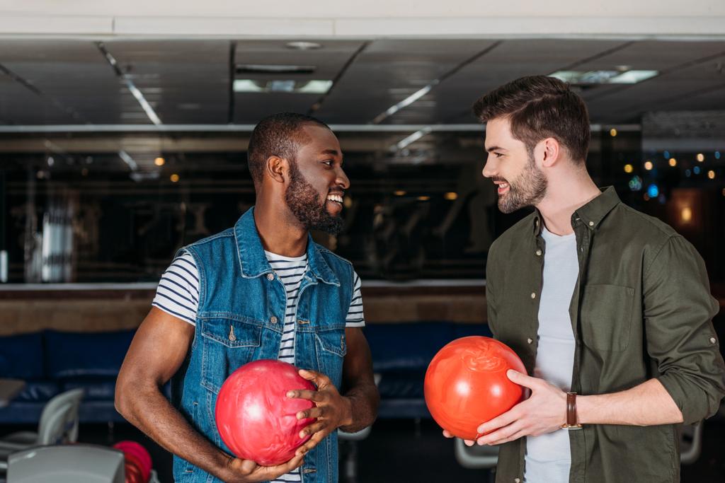 Gelukkig jonge mannen met ballen bij bowlingclub - Foto, afbeelding