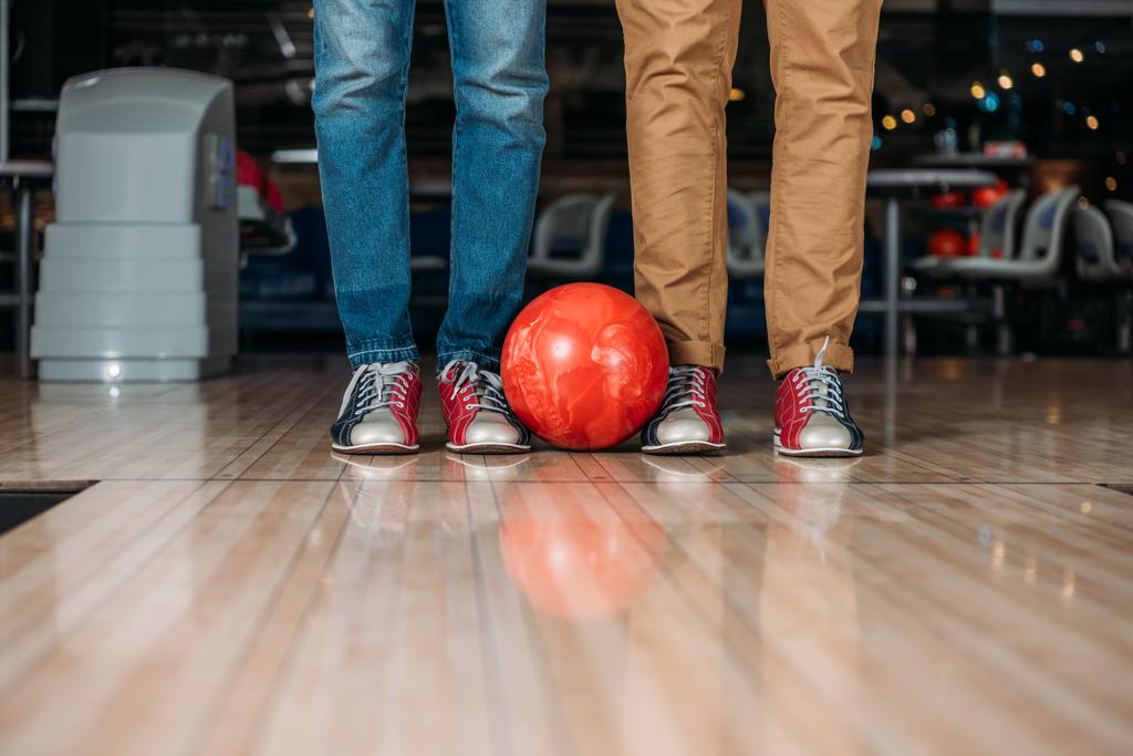 cropped shot of men standing in front of bowling alley with ball - Photo, Image