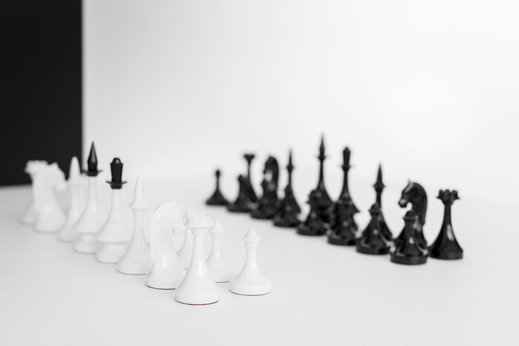 Chess cijfers op wit tafelblad in de buurt van zwart-witte muur - Foto, afbeelding