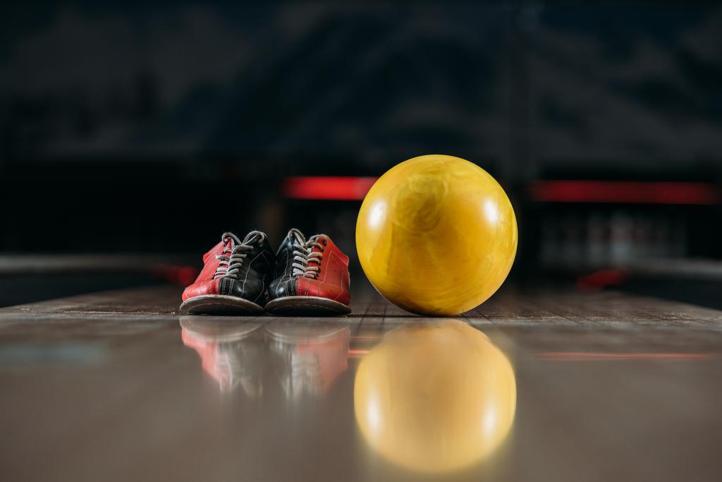 yellow bowling ball with shoes on alley at club - Photo, Image