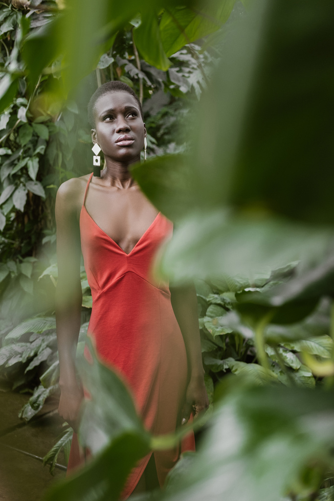 Selektiver Fokus stilvoller afrikanisch-amerikanischer Mädchen posiert in rotem Kleid im Garten - Foto, Bild