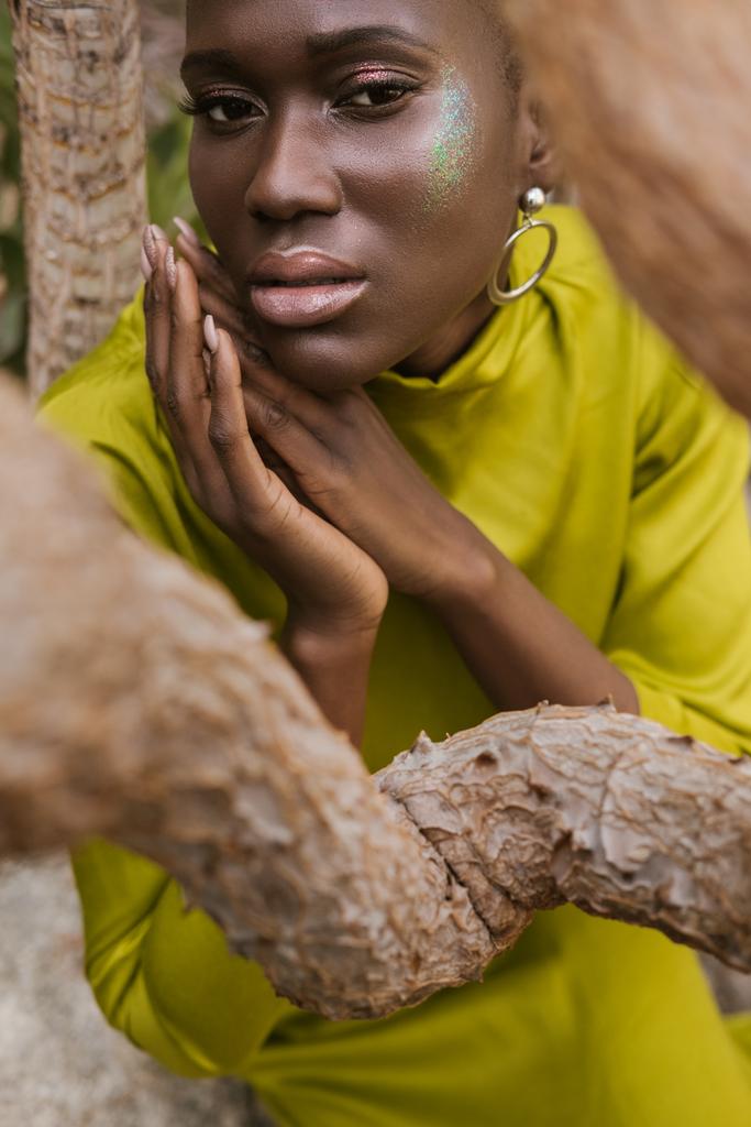 atrakcyjne african american kobieta z brokatem makijaż pozowanie w żółtej sukience - Zdjęcie, obraz
