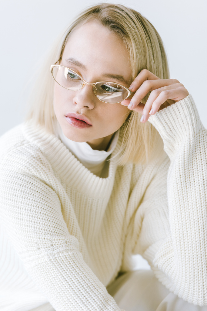 портрет красивої стильної блондинки в білому одязі, що торкається окулярів ізольовано на білому
 - Фото, зображення