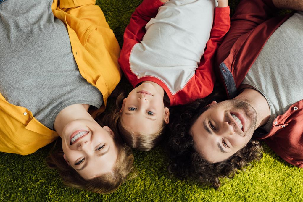 vista superior de la familia feliz con un niño acostado juntos y sonriendo a la cámara
  - Foto, imagen