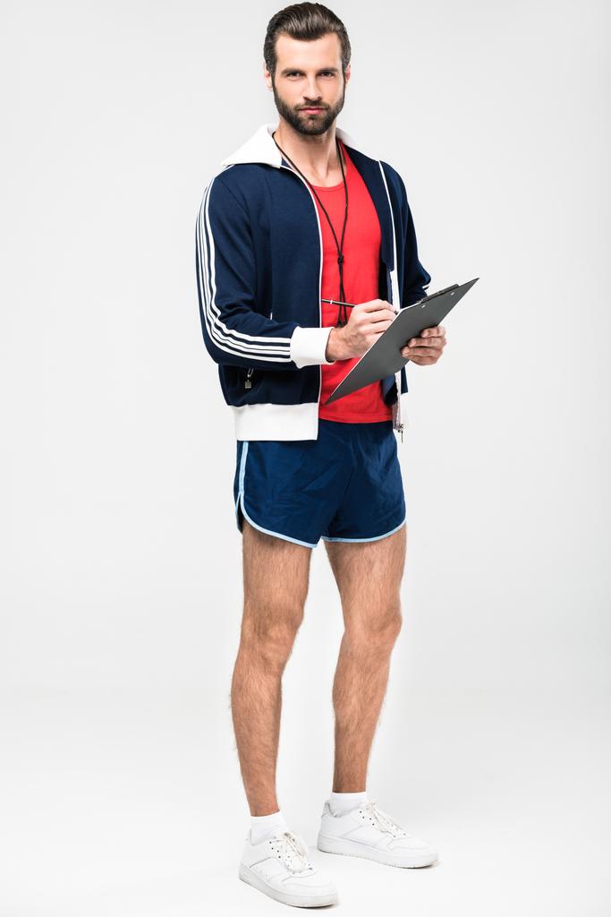 Sportlicher Trainer mit Trillerpfeife im Klemmbrett, isoliert auf weiß - Foto, Bild
