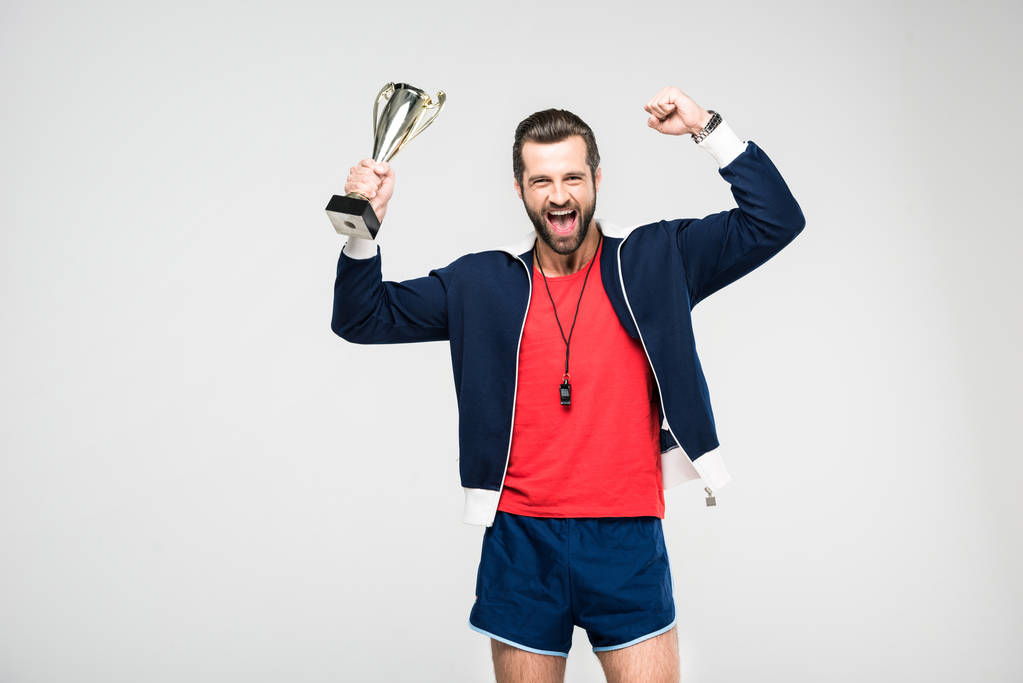 izgatott sportos edző, sikoltozik és holding kupa trófeát, elszigetelt fehér - Fotó, kép