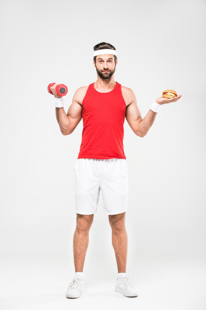 sportsman choosing fast food or healthy lifestyle, isolated on white - Photo, Image