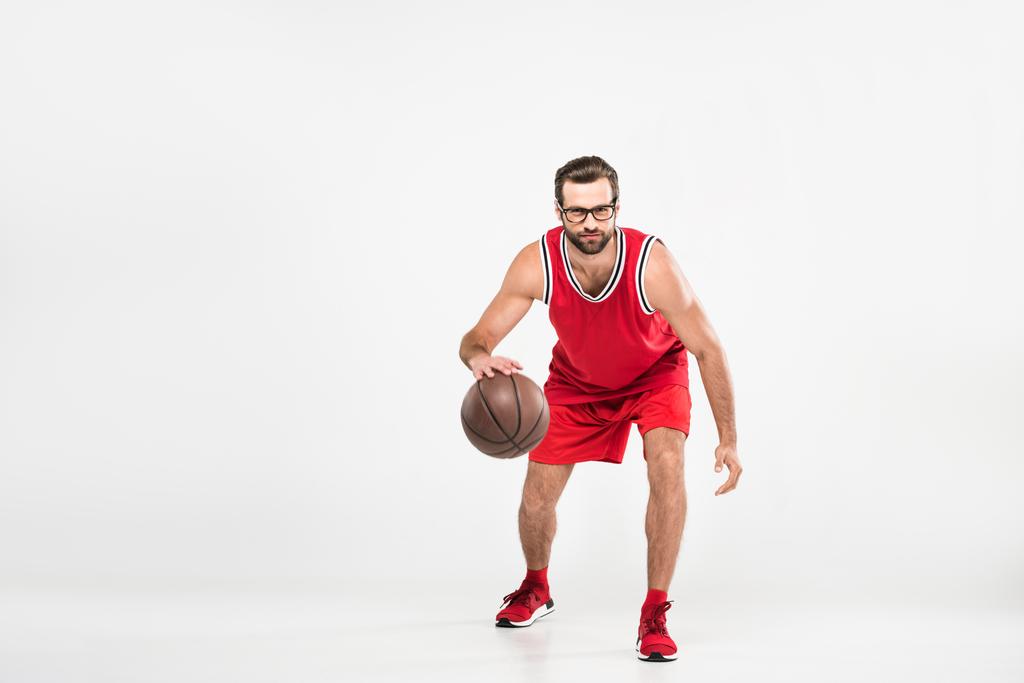 бородатый спортсмен в красной спортивной одежде и ретро-очках играет в баскетбол, изолированный на белом
 - Фото, изображение