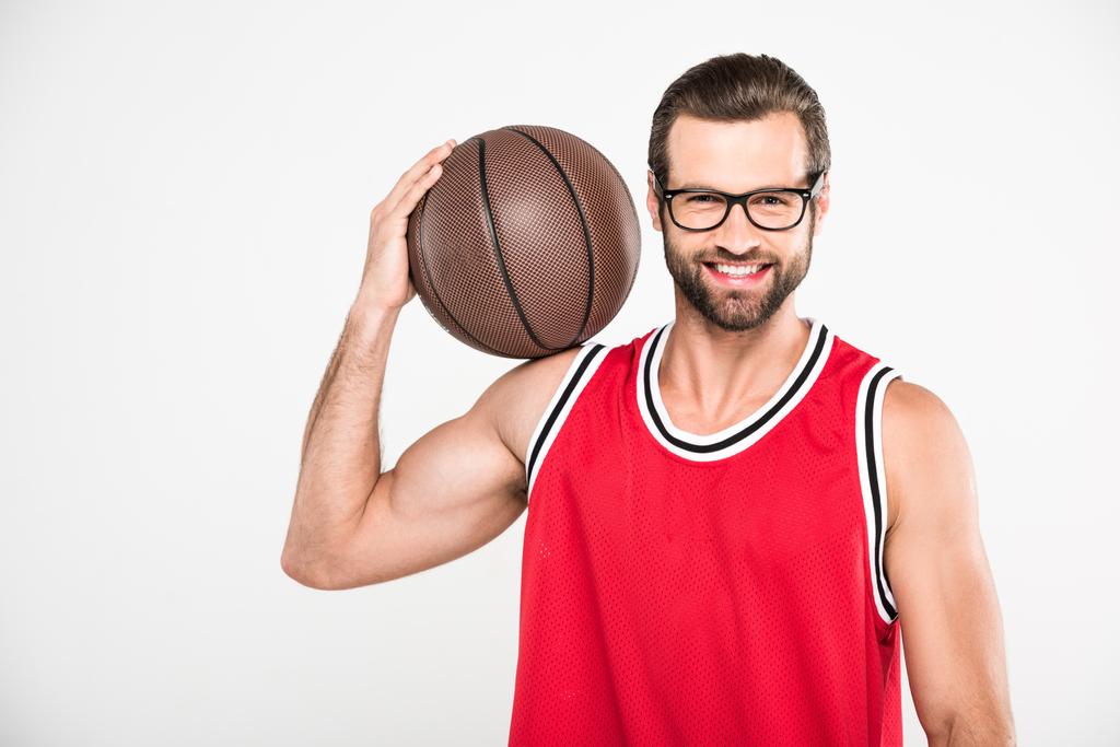 Veselá basketbalista v držení míče, izolované na bílém červená sportovní oblečení - Fotografie, Obrázek