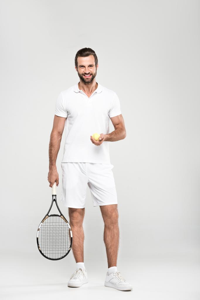 lächelnder Tennisspieler mit Ball und Schläger, isoliert auf grau - Foto, Bild