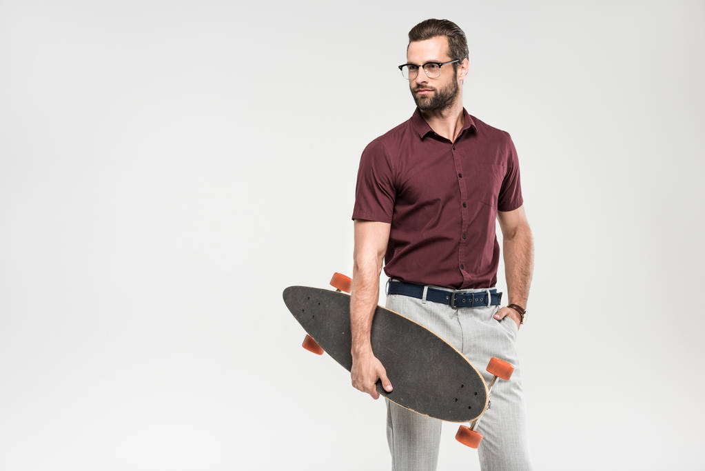 elegant handsome man posing with skateboard, isolated on grey - Photo, Image