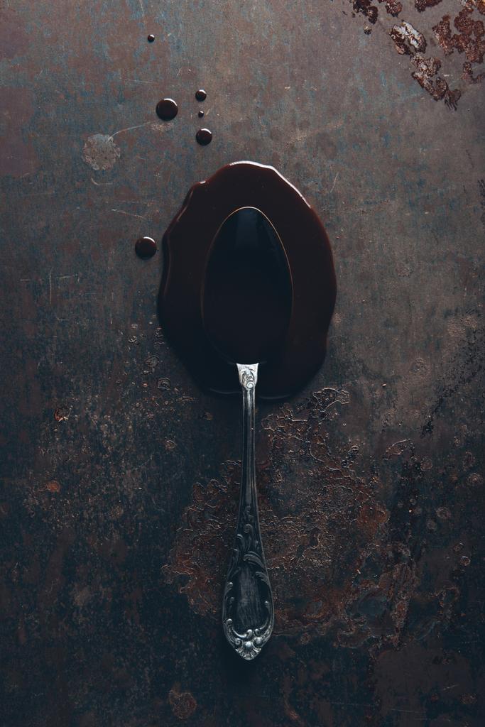 вид сверху на винтажную ложку и изысканный расплавленный шоколад на темной поверхности
 - Фото, изображение