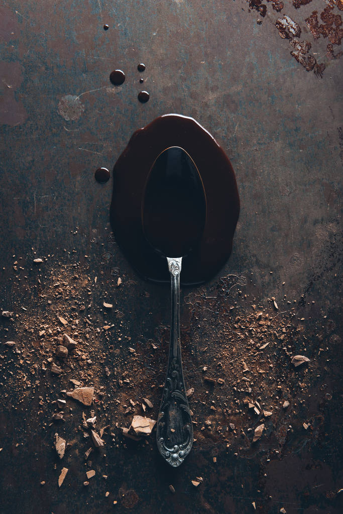 вид сверху на винтажную ложку и вкусный расплавленный шоколад на темной поверхности
 - Фото, изображение
