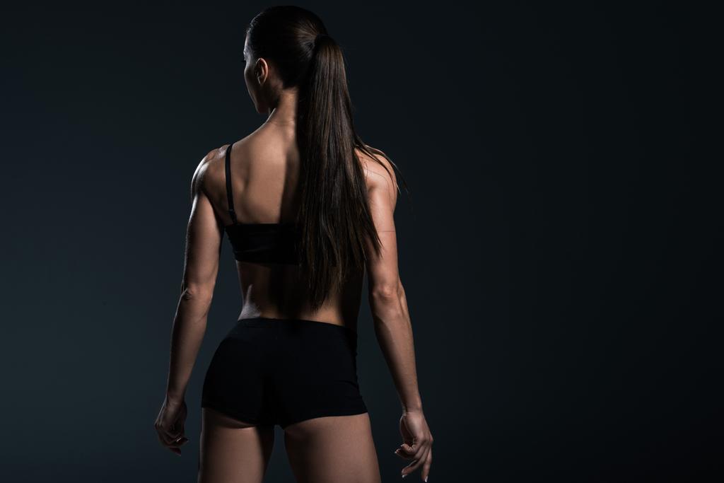 vue arrière du bodybuilder féminin posant en tenue de sport noire, isolé sur gris
  - Photo, image