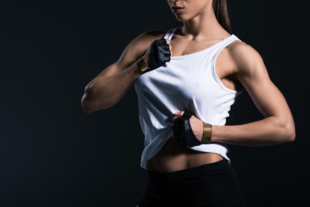 cropped view of muscular sportswoman showing abs, isolated on black   - Photo, Image