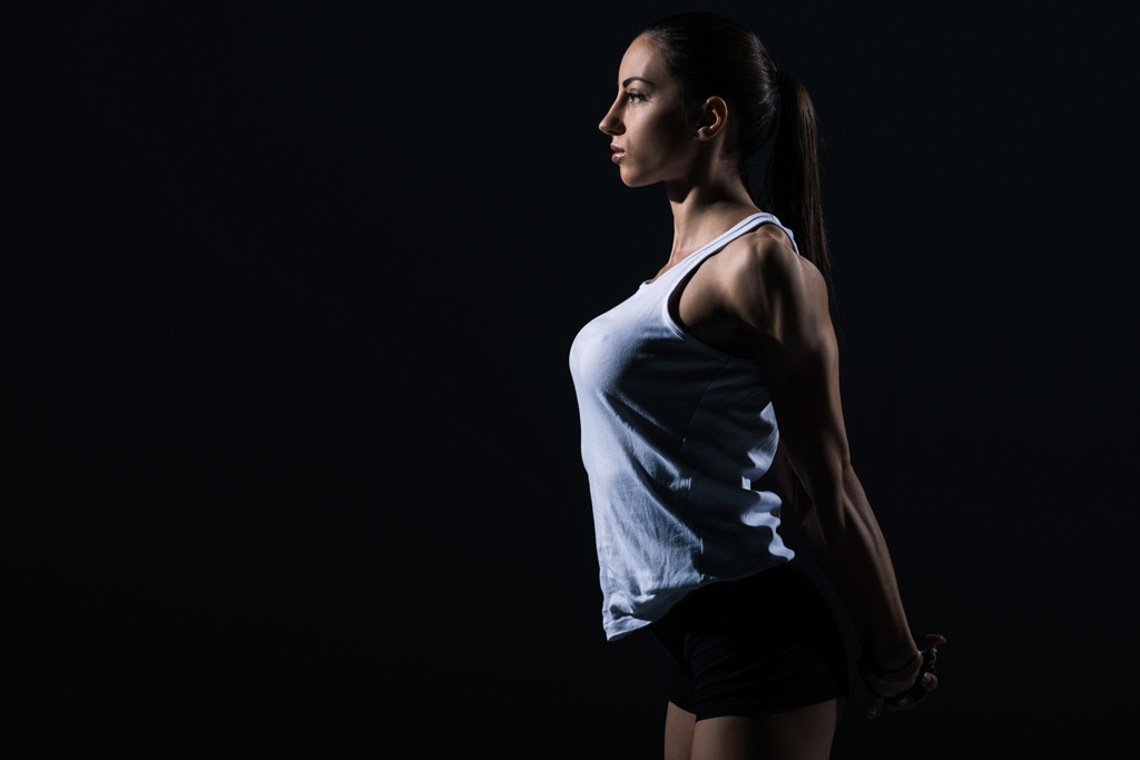 krásné sportovní sportovkyně Natahování paží, izolované na černém    - Fotografie, Obrázek