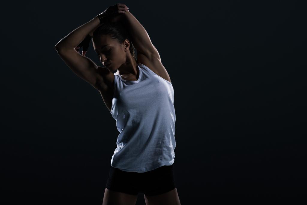 beautiful young female bodybuilder stretching, isolated on black    - Photo, Image