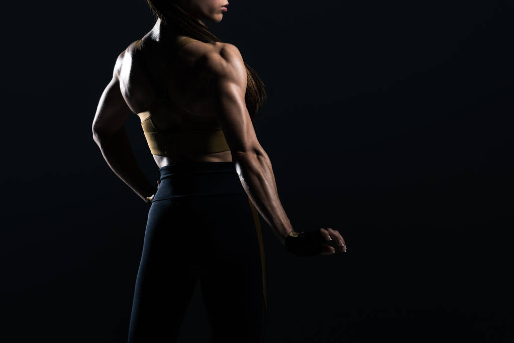 γυναίκα bodybuilder, ποζάρει και να δείχνει τους μυς, απομονώνονται σε μαύρο    - Φωτογραφία, εικόνα